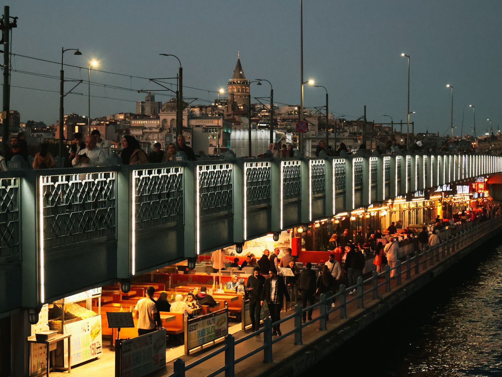 Night view of Galata Bridge bustling with people and distant Galata Tower in Istanbul. — A Guide for Choosing the Right Onlin