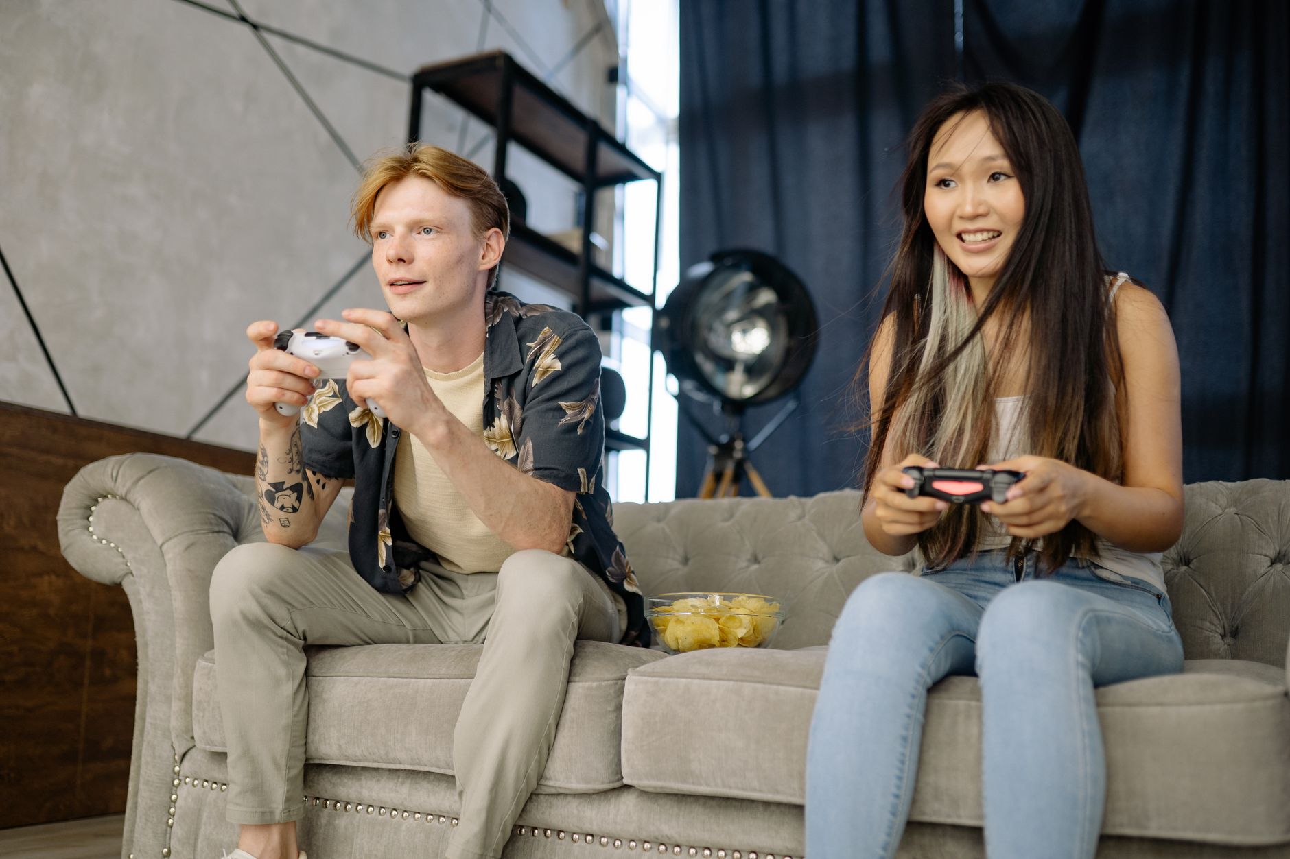 Two friends engaged in video gaming at home, enjoying leisure time on a comfortable couch. — About The Benefits And Offers Of