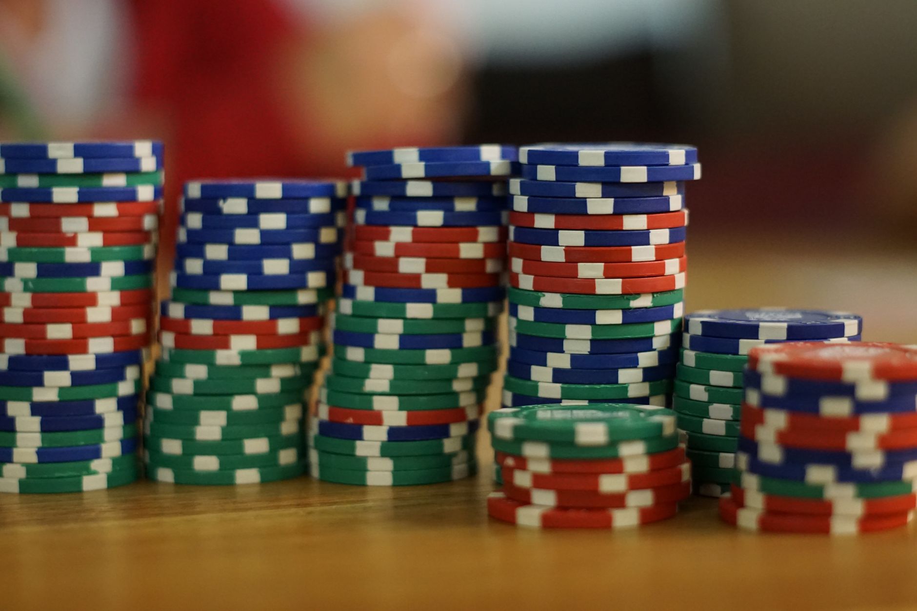 A close-up view of colorful stacked poker chips on a wooden table, perfect for casino themes. — Art of winning money and whic
