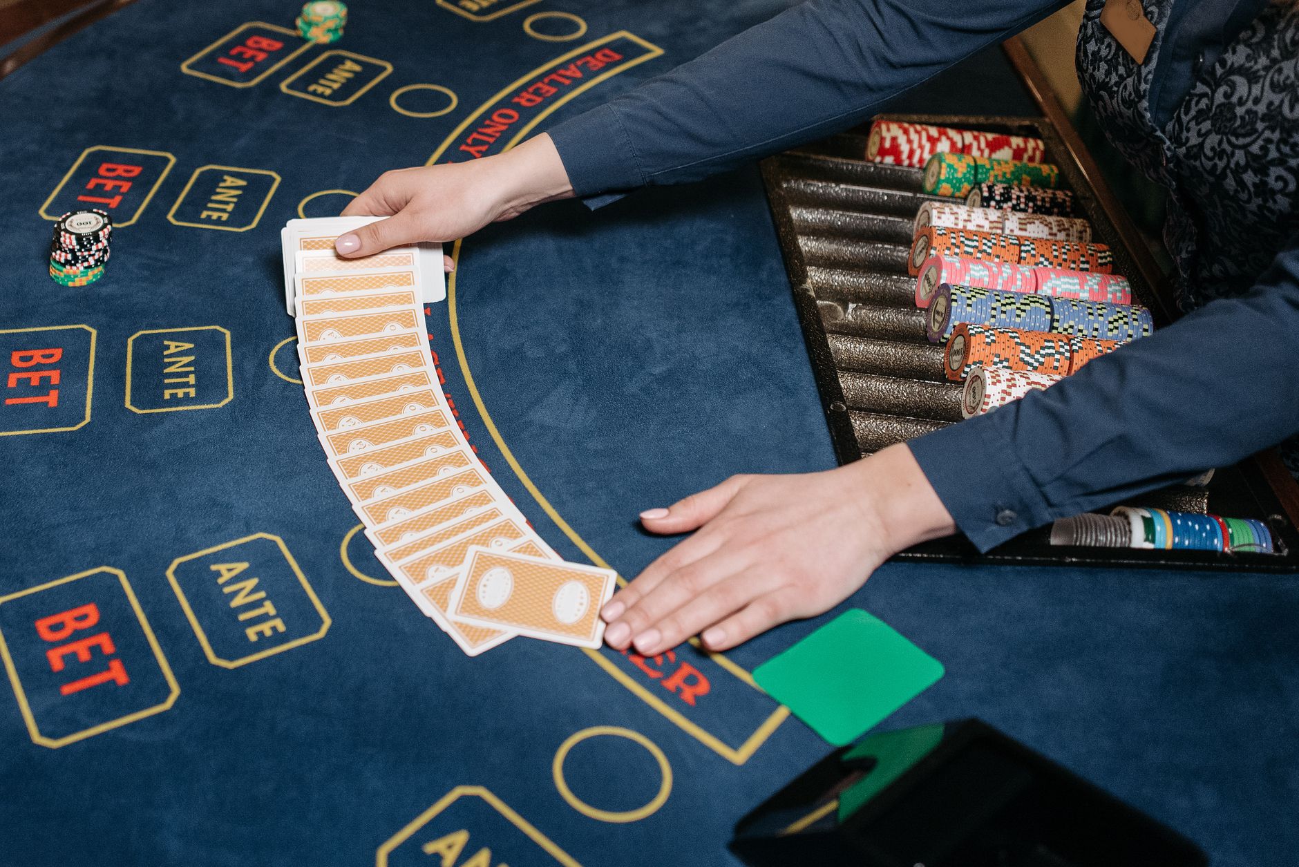 A casino dealer skillfully spreads playing cards on a gaming table, surrounded by colorful poker chips. — Do you know the pri