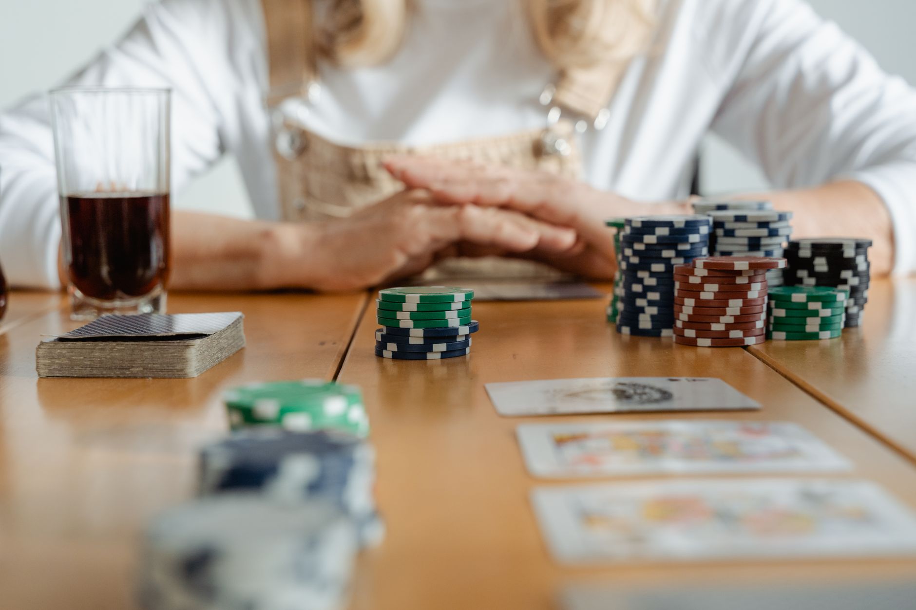 Senior woman playing poker with cards and chips on a wooden table indoors. — Essential things that you need to always conside