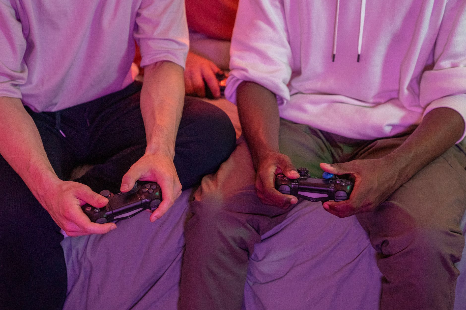 Two friends playing video games together at home, using controllers. — Going Through The Perks Of Soccer Betting In An Online