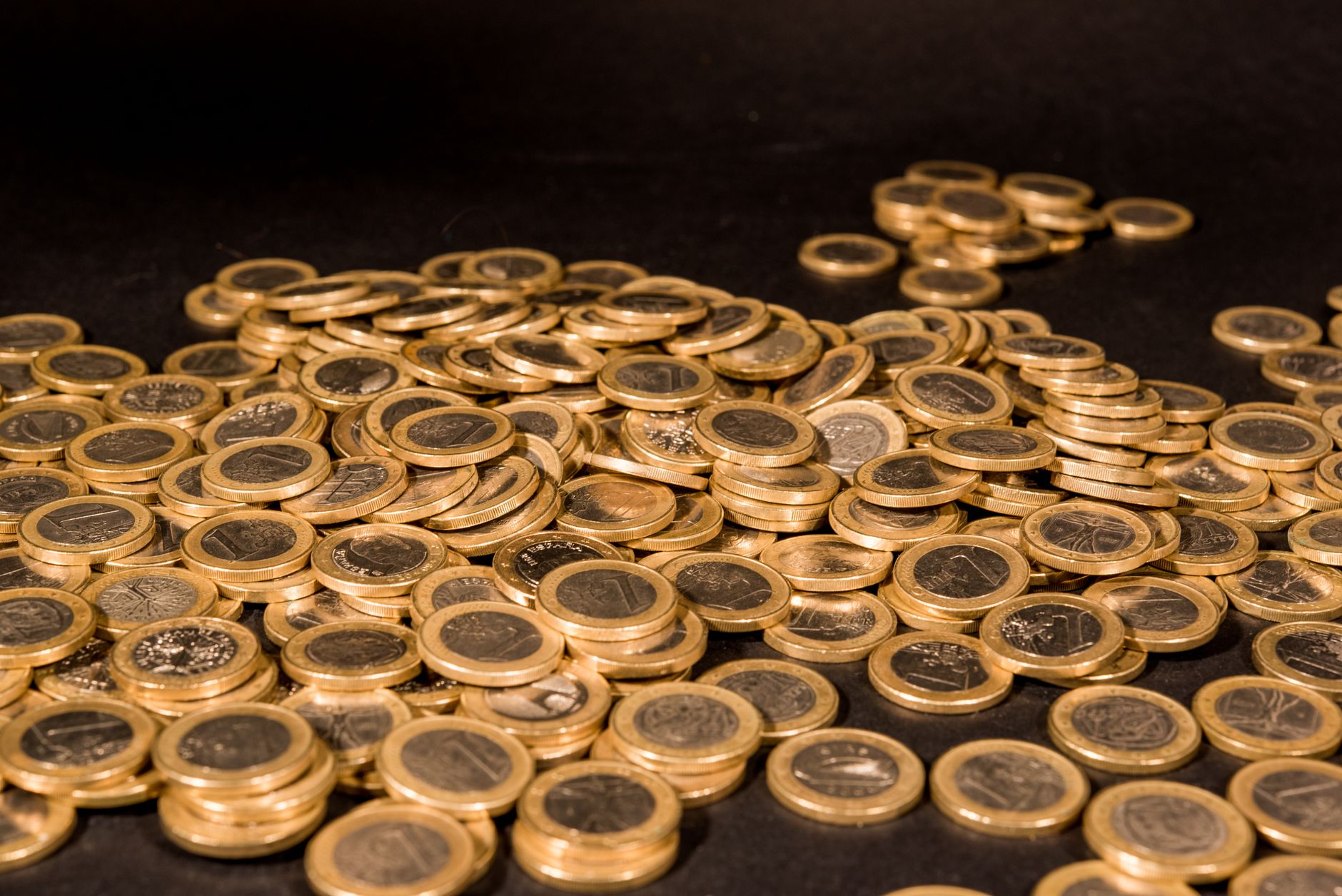 Close-up of a pile of Euro coins scattered on a black surface, representing wealth and finance. — How playing football gambli