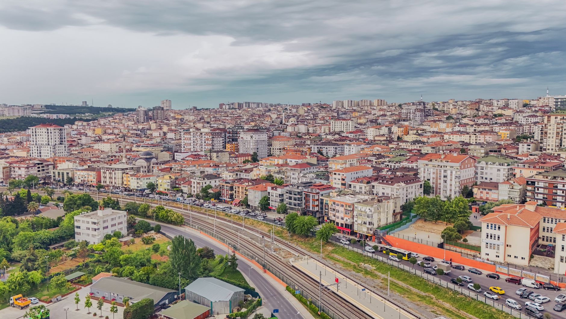 Aerial view of dense urban architecture with roads and greenery under cloudy skies. — How To Use Google Duo On A Chromebook