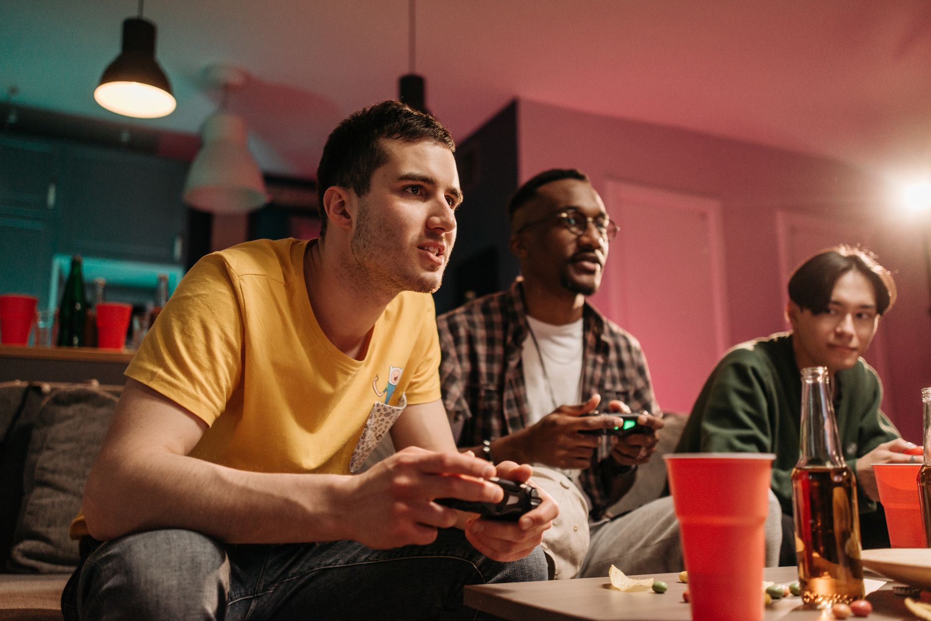 Diverse group of young adults playing video games on a cozy sofa with refreshments. — How User Engagement and Technology Are