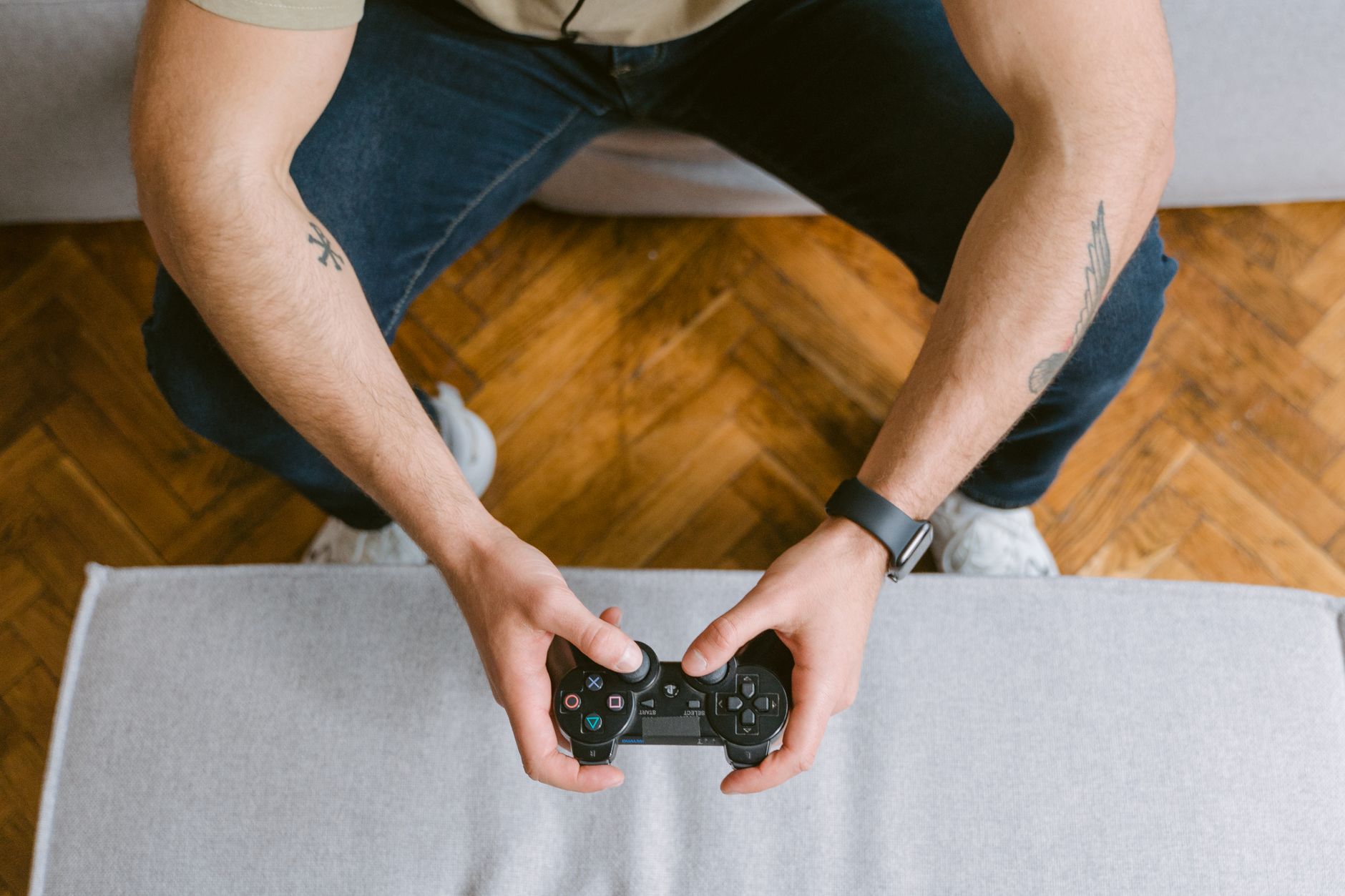 A man sitting on a couch holds a game controller, ready to play video games. — Huc99: 5 Ways To Win At Online Casino