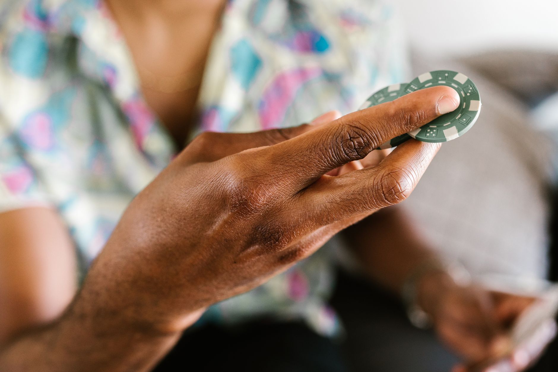 A detailed view of a hand holding a poker chip with a blurred background, emphasizing gambling and fun. — Kinds of Electronic