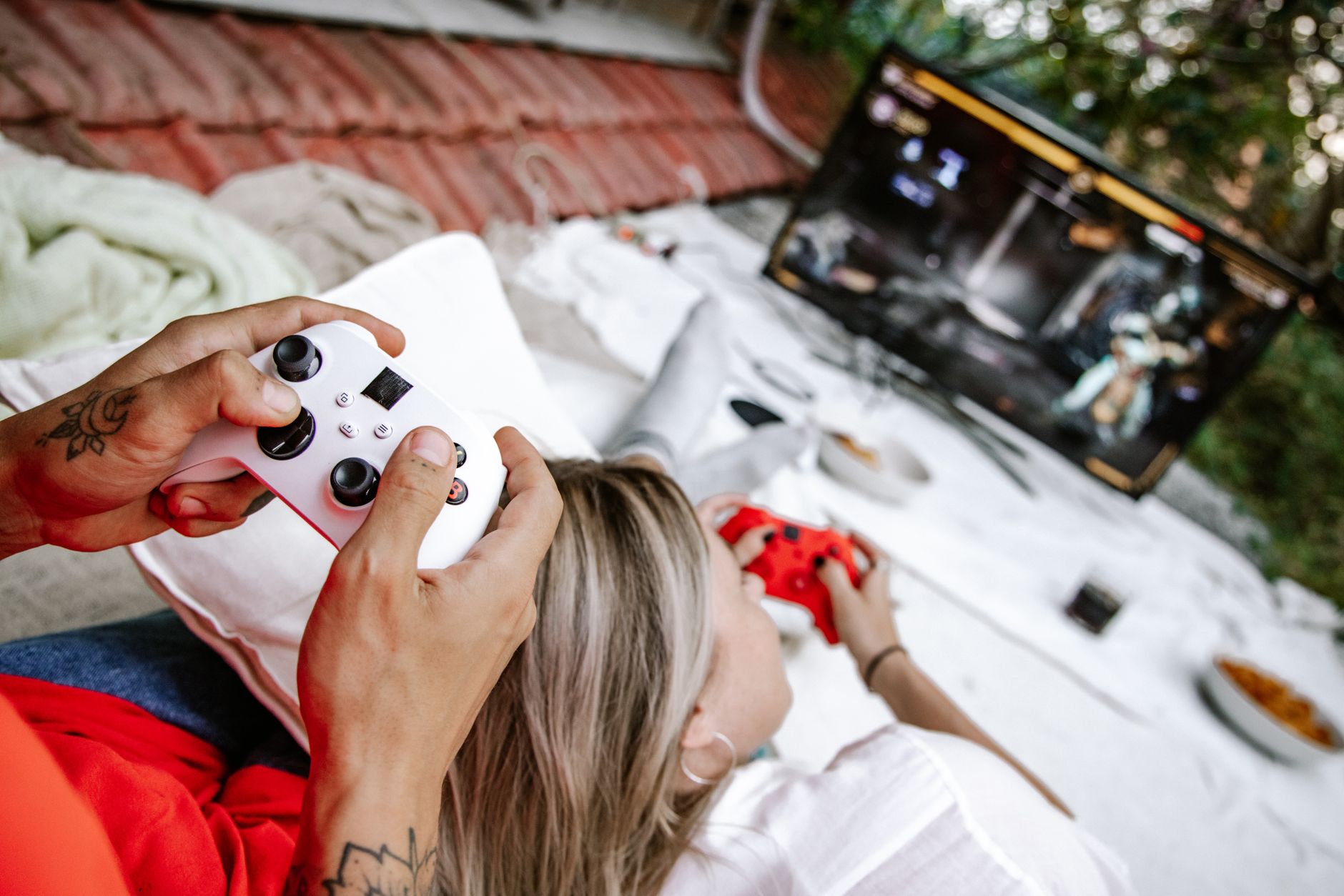 A couple playing video games outdoors, focusing on the controllers and screen. — PG-SLOT: What You Need To Know Before Playin