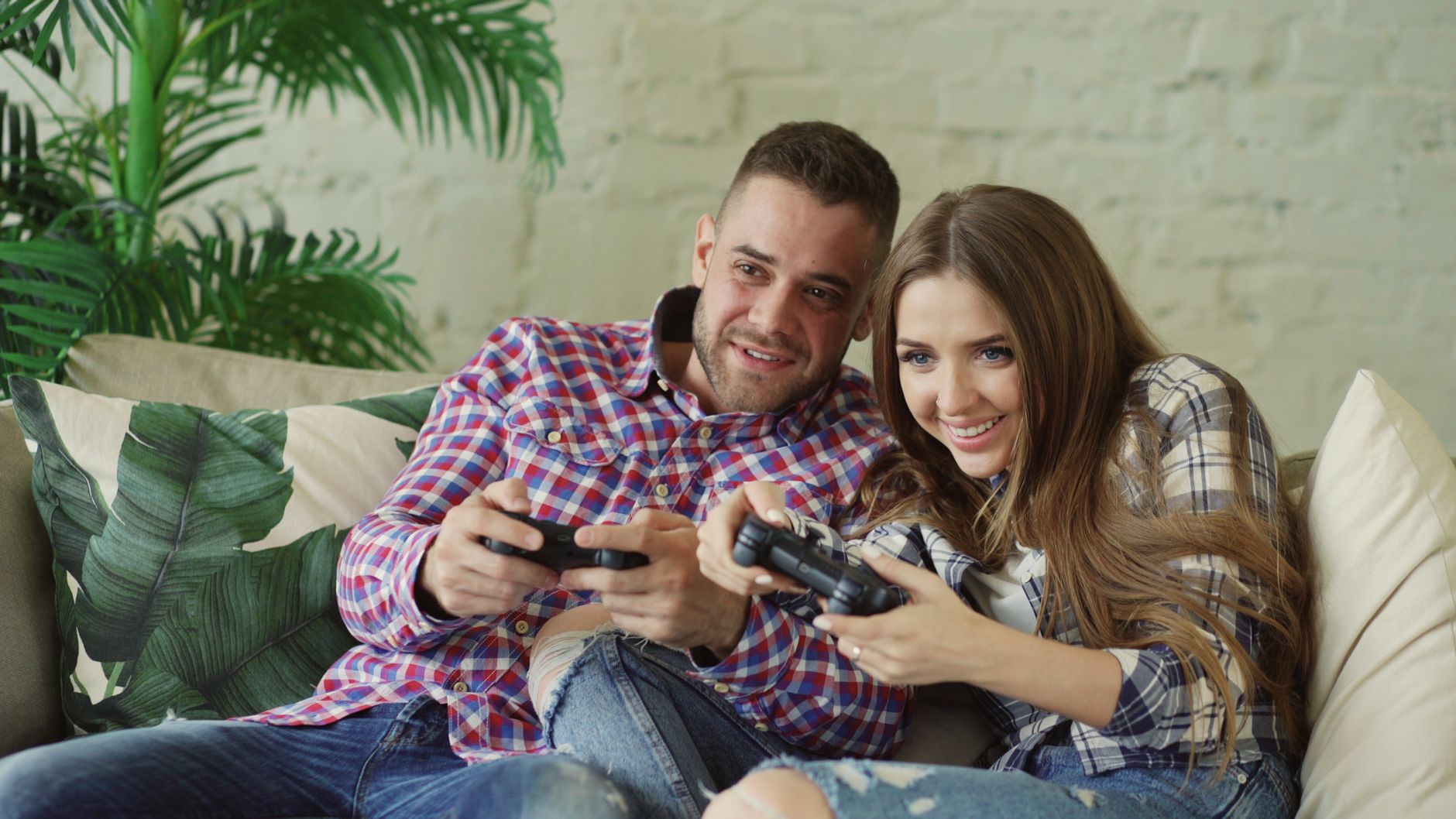 Happy couple enjoying video games together at home on a cozy sofa. — Play and Win with Fun88