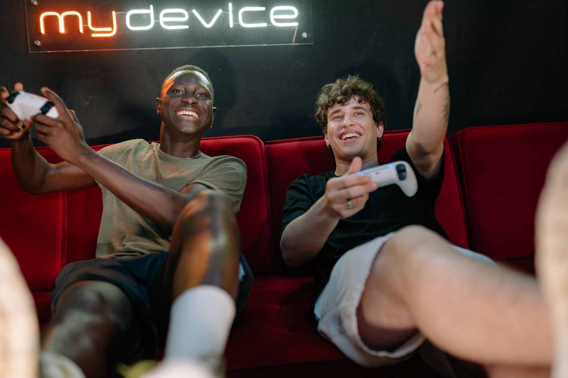Two friends having fun and playing video games on a couch indoors. — The Benefits Of Using toto site When Playing In Online C