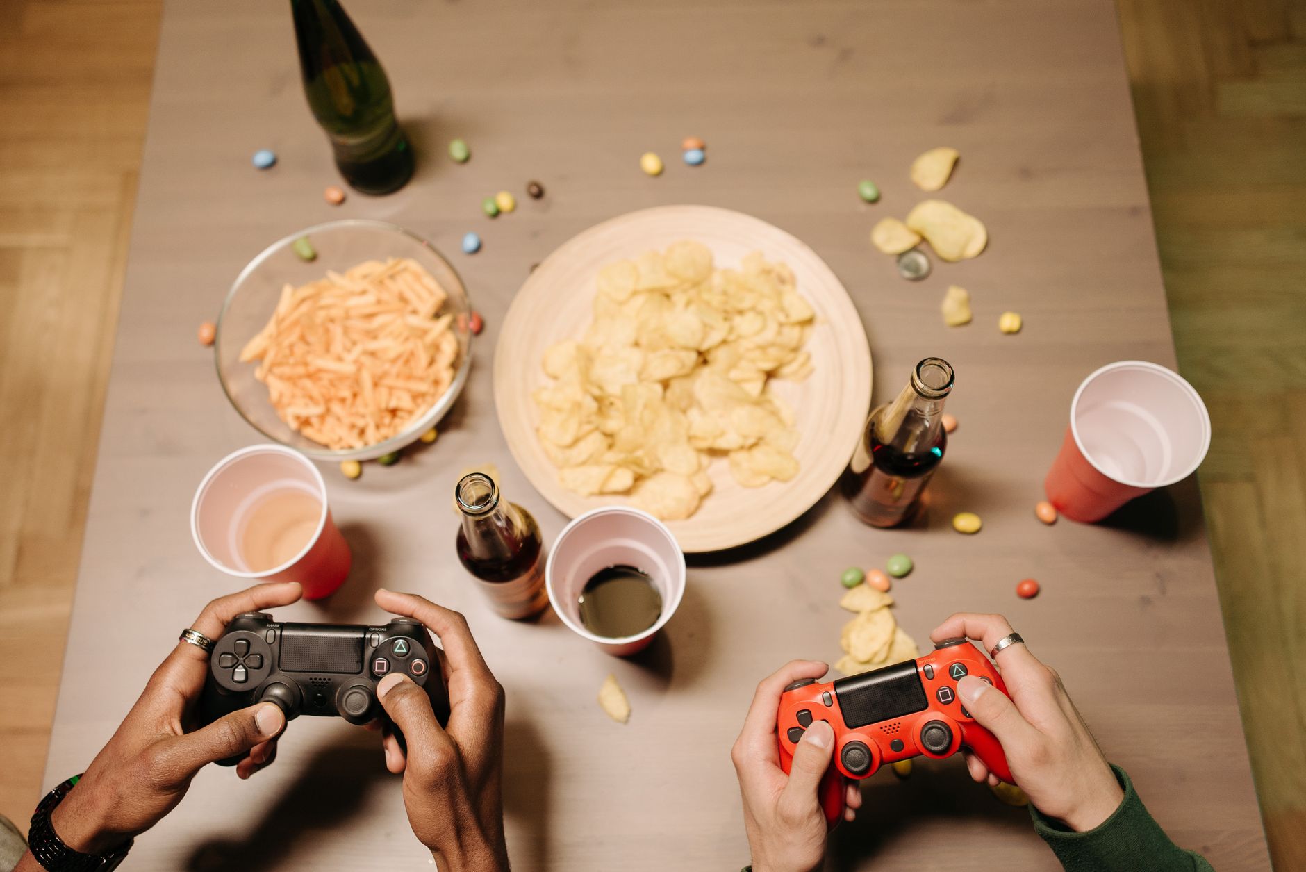 Two gamers playing video games with snacks and drinks on table, a perfect setup for gaming night. — Things You Need To Know A