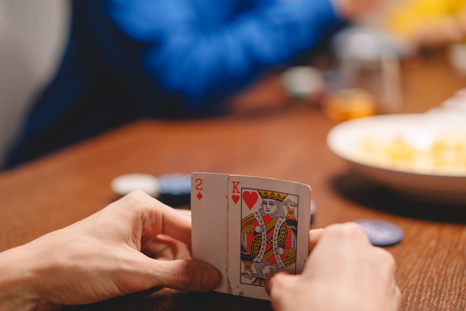 Close-up of a person holding playing cards during a poker game, focused on strategy and excitement. — Ultimate Guide:Poker Ta