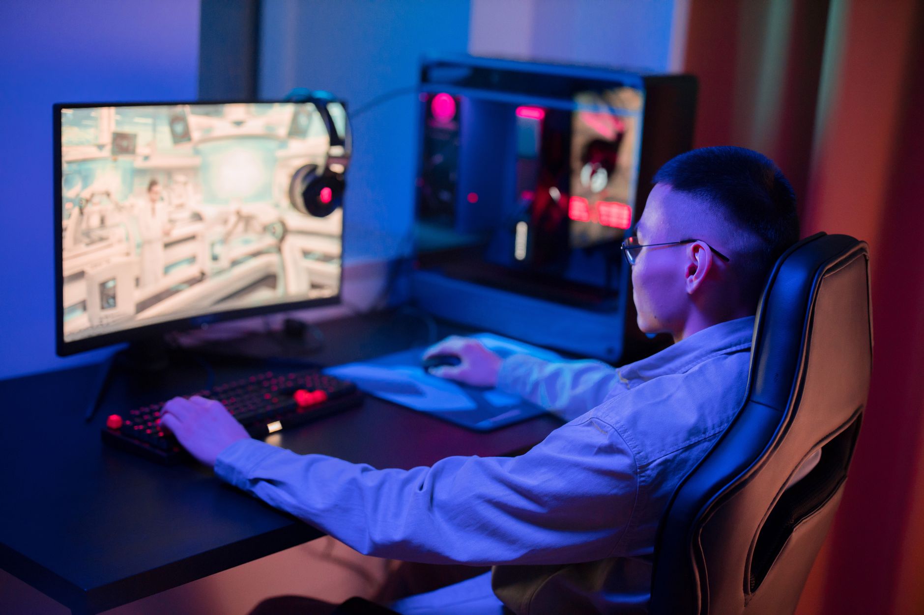 A young man intensely gaming on a computer at home, showcasing a modern gaming setup. — Why Must People Consider Joker123 for
